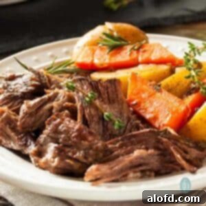 Meltingly Tender Slow Cooker Chuck Roast 9 A rustic platter overflowing with tender chuck pot roast, roasted carrots, and potatoes, creating a visually appealing and hearty meal.