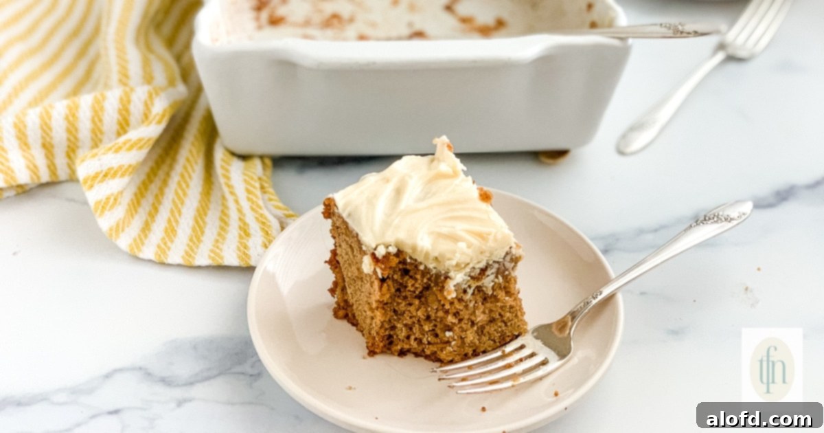 A perfectly portioned slice of old-fashioned apple cake on a white plate, accompanied by a fork, ready to be enjoyed.