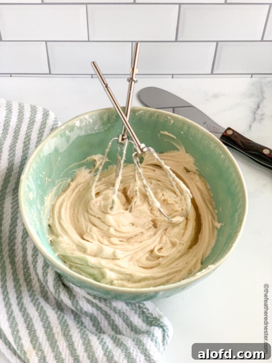 A green mixing bowl containing sourdough cake batter, with electric mixer beaters resting within.