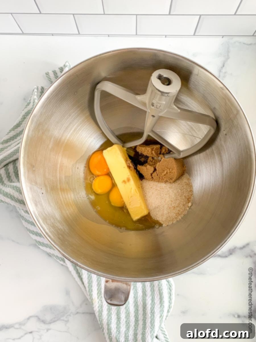 A mixing bowl full of butter, eggs, and both brown and white sugars, ready to be creamed into a smooth batter.