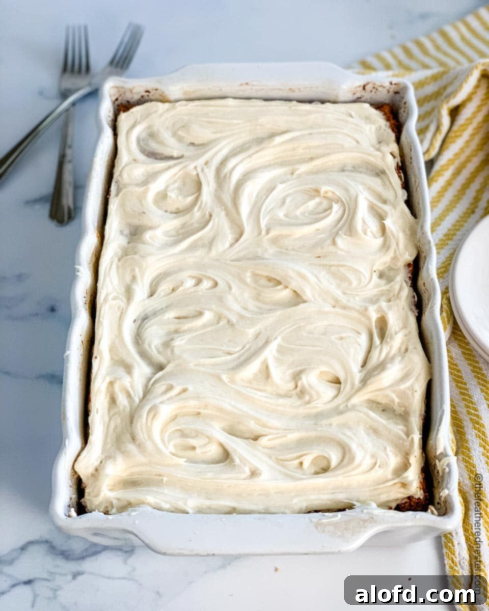 A pan of frosted old-fashioned apple cake sits next to elegantly arranged serving plates and forks, ready for guests.