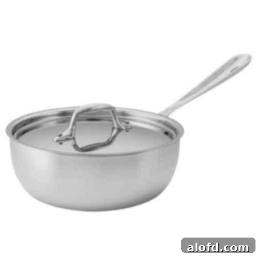A gleaming stainless steel saucier pan with its distinctive flared sides, perfect for whisking delicate sauces. This essential kitchen tool ensures even heating and smooth culinary creations, making it a valuable addition to any home chef's collection.