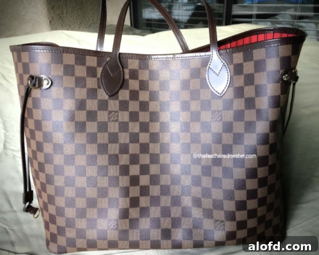 My Unfiltered Review of the Louis Vuitton Neverfull 13 A stylish Louis Vuitton Neverfull tote with its vibrant cerise interior lining, elegantly posed.