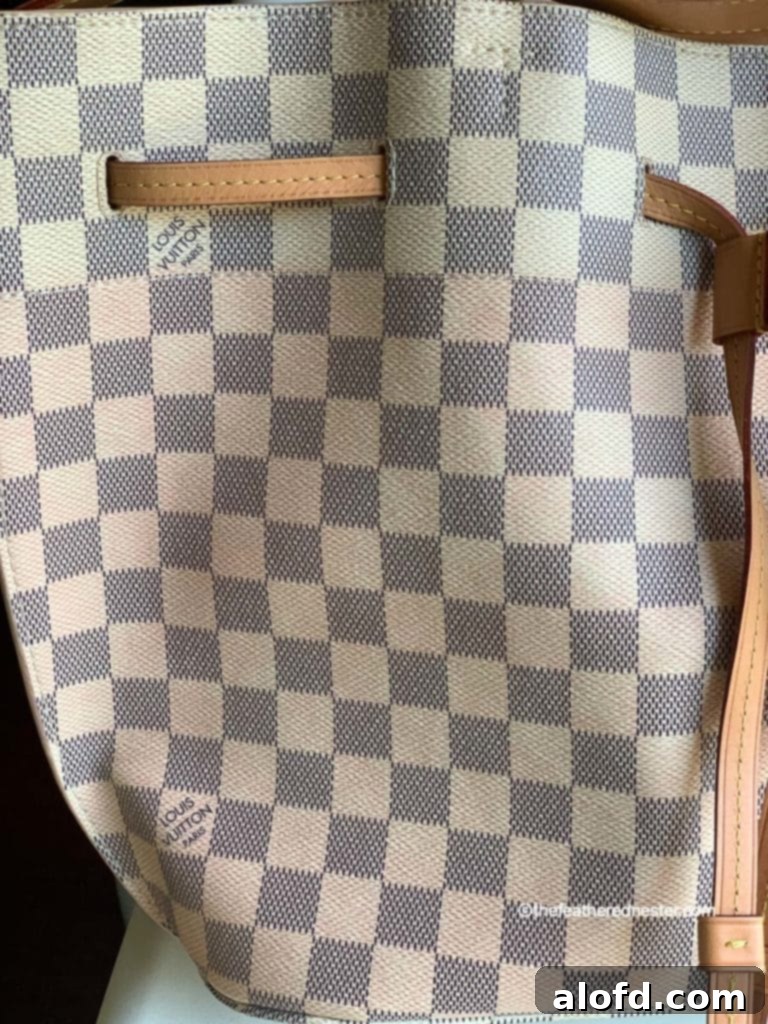 My Unfiltered Review of the Louis Vuitton Neverfull 10 A close-up image showing pink dye bleeding onto the white canvas of a Louis Vuitton Girolata handbag, highlighting a manufacturing defect.