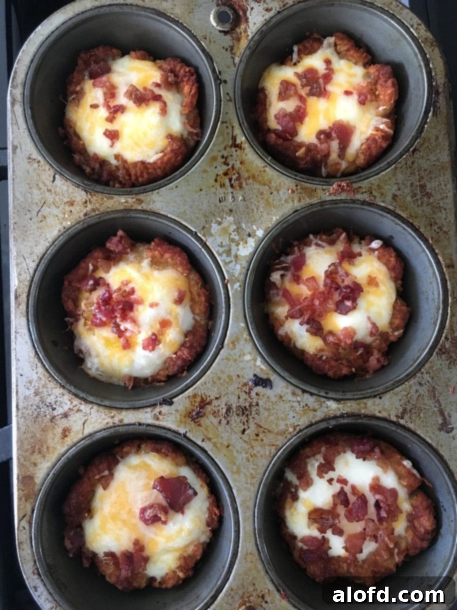 Crispy Tater Tot Egg Bites 6 A close-up of beautifully baked tater tot egg cups, fresh out of the muffin pan, displaying their crispy edges, perfectly set eggs, melted cheese, and crumbled bacon ready to be served.