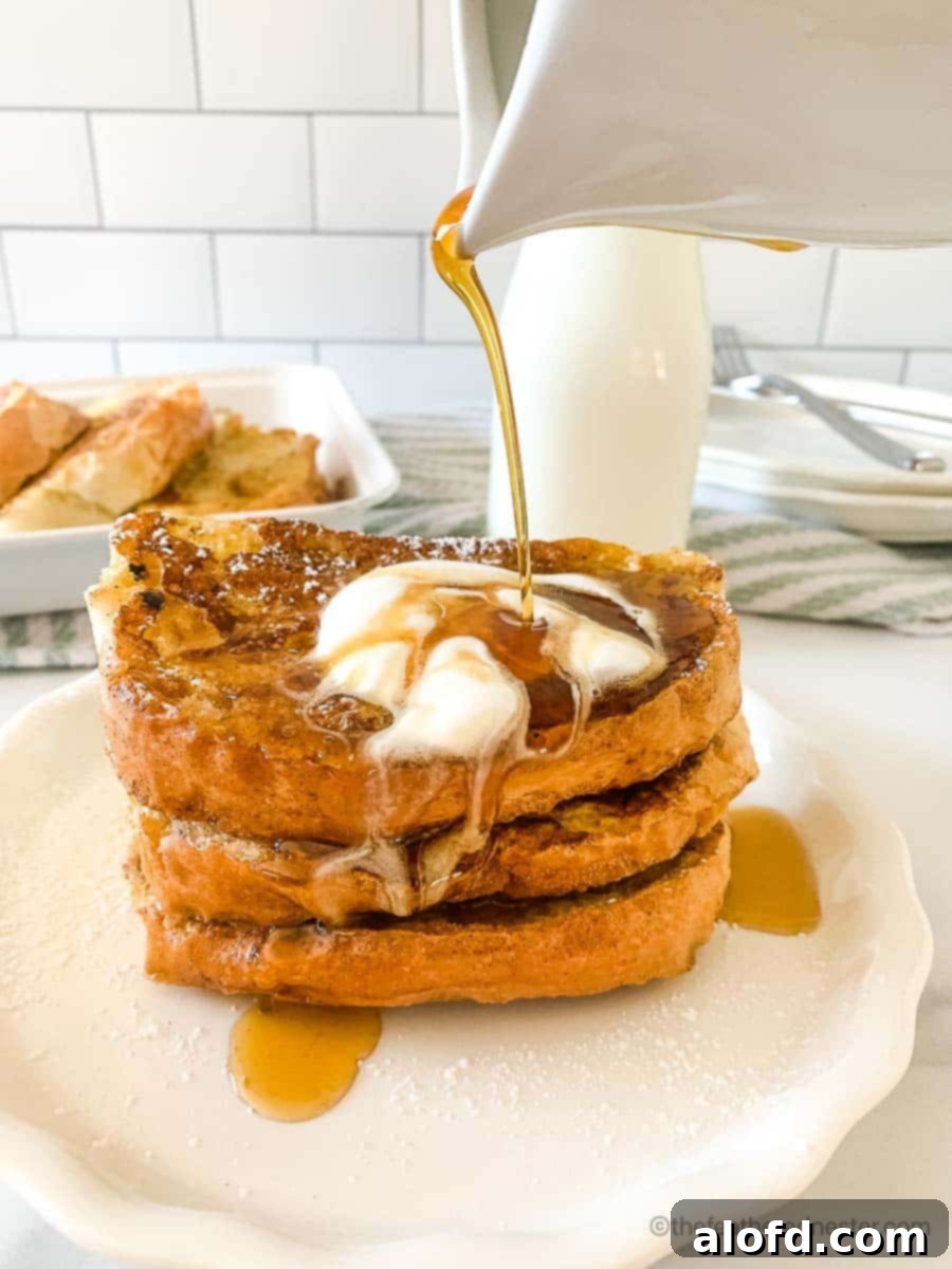 Tangy Sourdough French Toast 3 Pouring maple syrup over stack of griddled bread topped with butter.