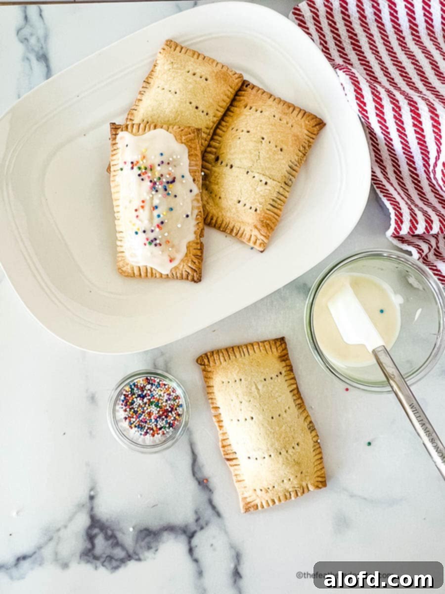 Untamed Berry Breakfast Pastries 8 A hand frosting homemade blueberry pop tarts with a simple white icing, ready for serving.