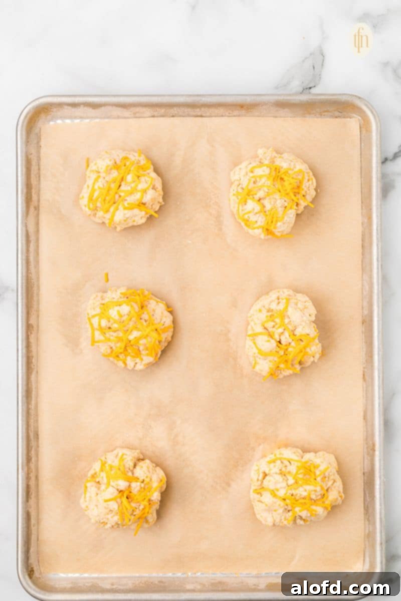Bisquick Garlic Cheddar Biscuits 12 A dollop of cheddar biscuit dough on a baking sheet lined with parchment paper.