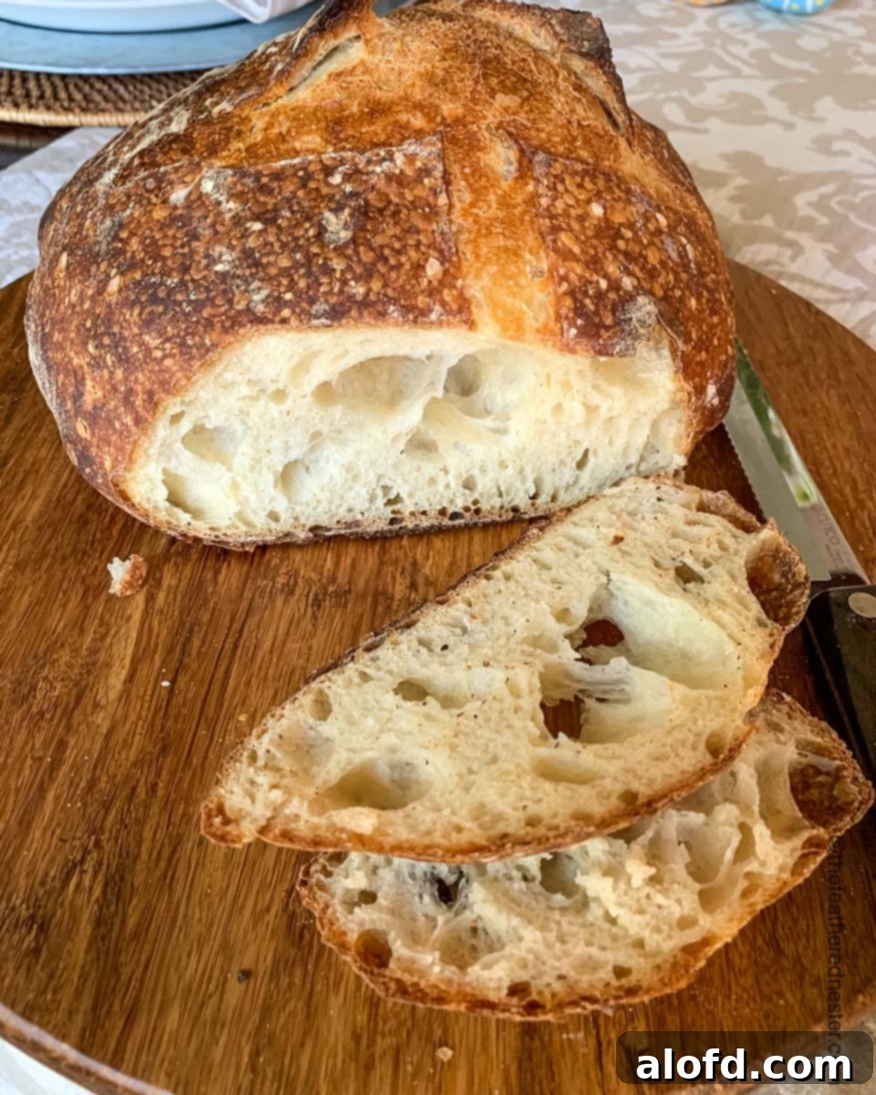 A sliced loaf of sourdough bread baked in a Dutch oven, showing its airy interior.