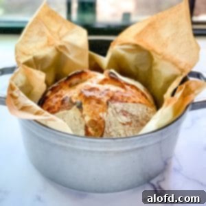 Staub Dutch oven with a loaf of overnight sourdough bread cooling, showcasing a beautiful golden crust.