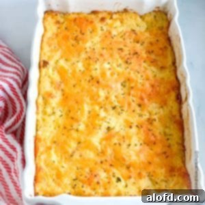 Homestyle Hash Brown Casserole 8 White casserole dish of Cracker Barrel hash brown casserole with a striped red cloth beside it, freshly baked and golden.