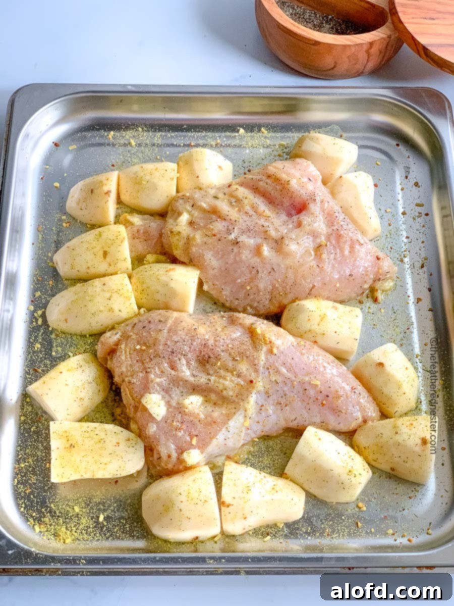 A robust roasting pan containing marinated turkey tenderloins alongside perfectly cut potatoes, ready for the oven.