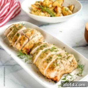 A serving plate featuring perfectly cooked turkey tenderloins, complemented by a striped cloth and a bowl of roasted potatoes in the background.