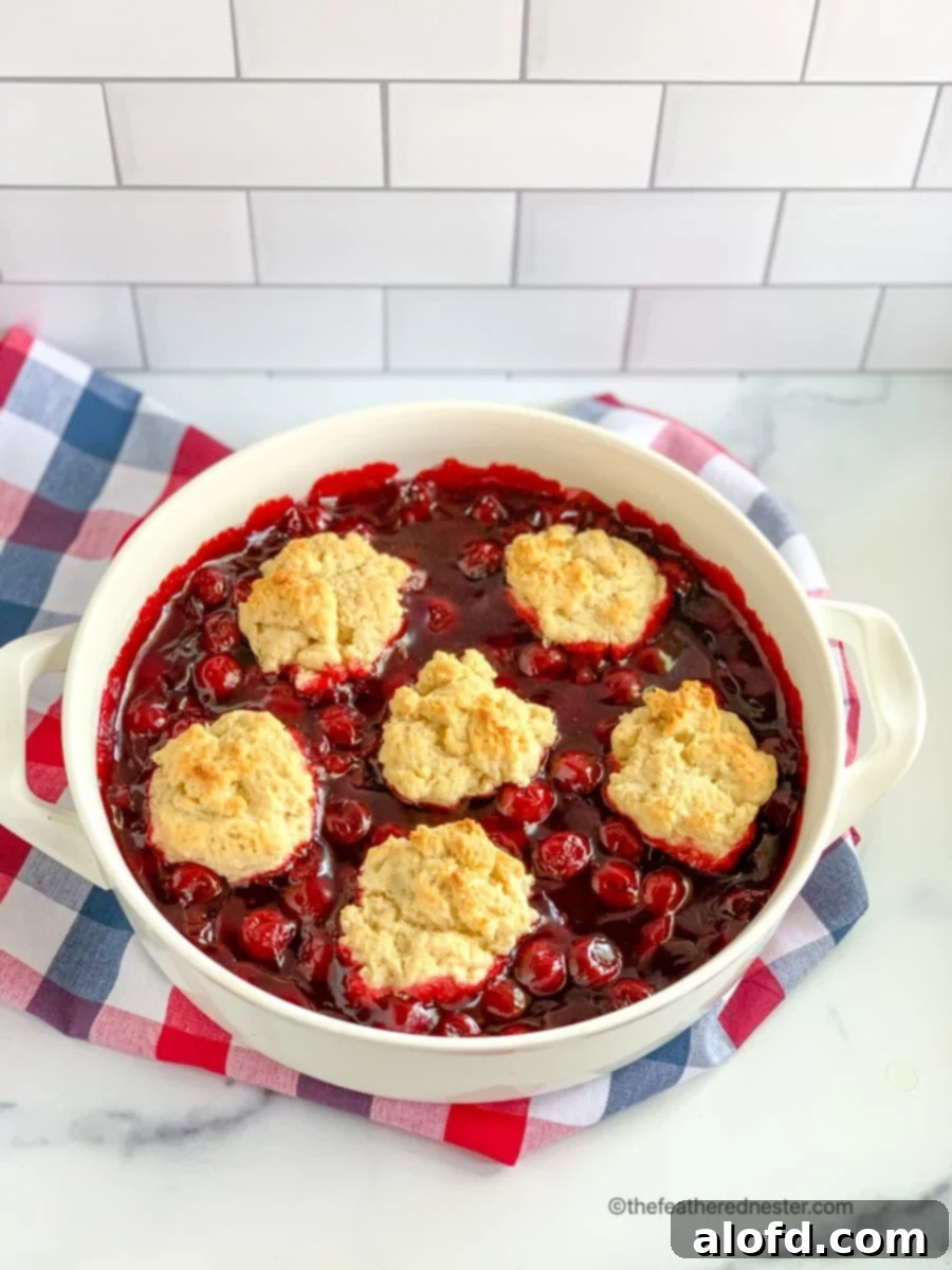 White casserole dish of homemade Bisquick cherry cobbler, showing its vibrant red filling and golden topping.