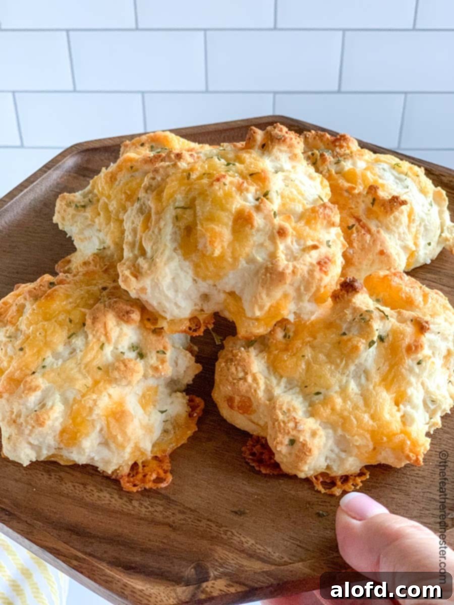 A wooden tray of golden-brown cheddar bay biscuits, inviting and warm.