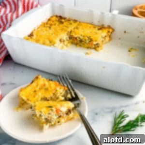 Ultimate Hash Brown Breakfast Bake 12 A casserole dish of hash brown casserole with a plate of the egg casserole ready to serve and a striped red towel in the background.