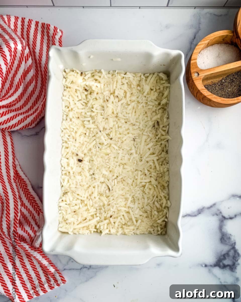 Ultimate Hash Brown Breakfast Bake 4 Thawing frozen hash browns spread out on a baking sheet to prepare for a casserole.