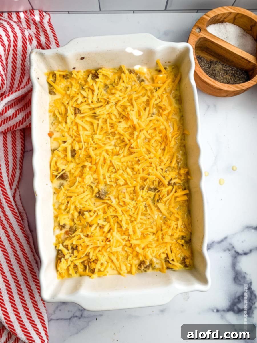 Ultimate Hash Brown Breakfast Bake 9 The casserole dish topped with a generous layer of shredded cheese, poised for baking to golden perfection.