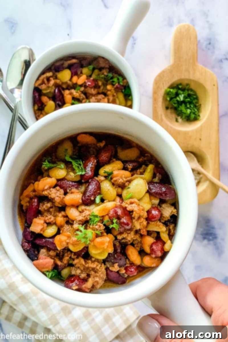 a bowl of crock pot calico beans with another bowl of beans in the background.
