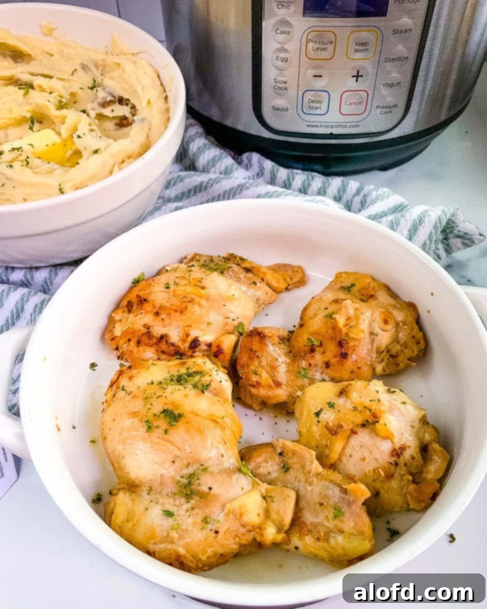 Tender Instant Pot Chicken Thighs and Potatoes 2 A serving platter of chicken thighs with a bowl of mashed potatoes and Instant Pot in the background.