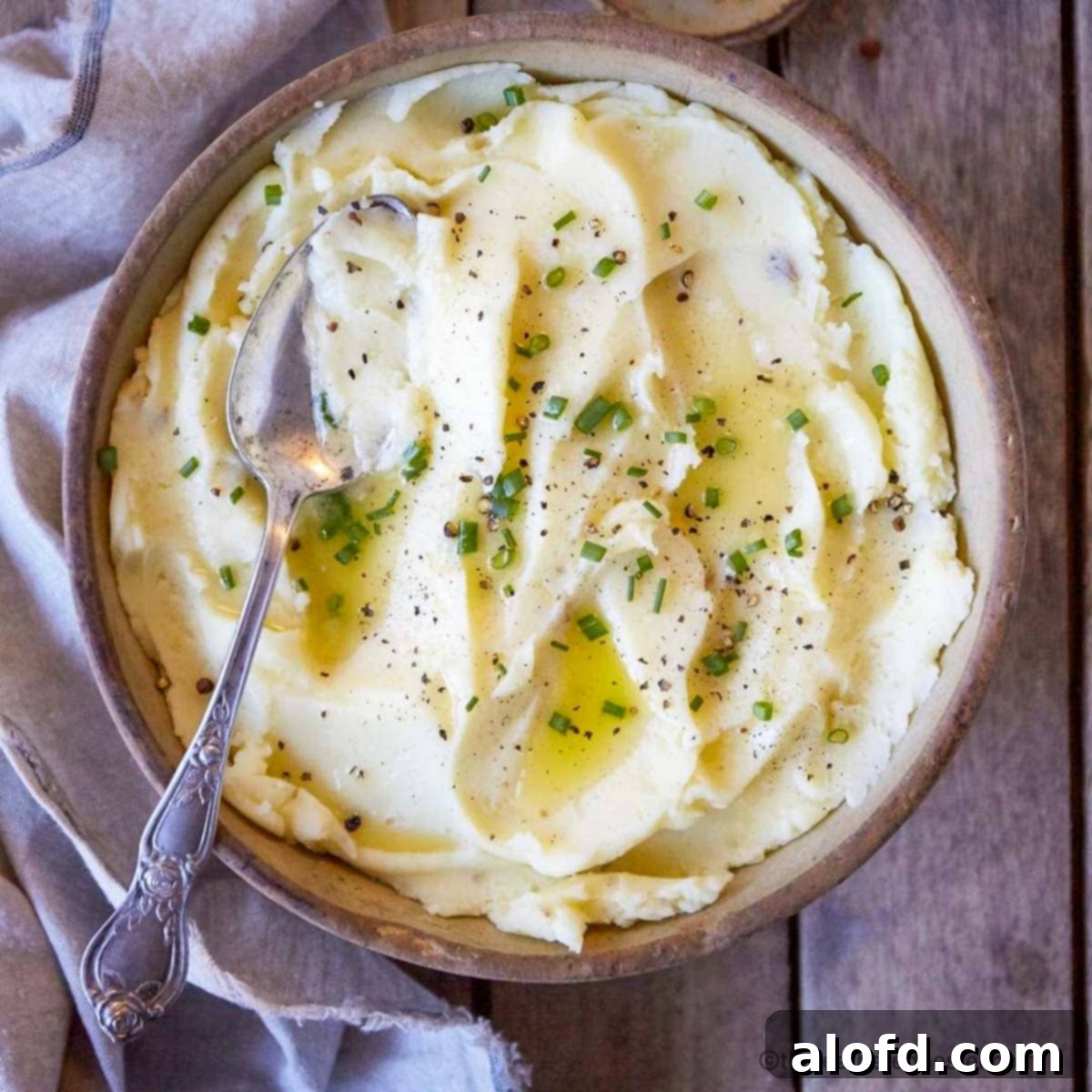 Tender Instant Pot Chicken Thighs and Potatoes 9 A closeup of a bowl of mashed potatoes with garlic butter and chives.