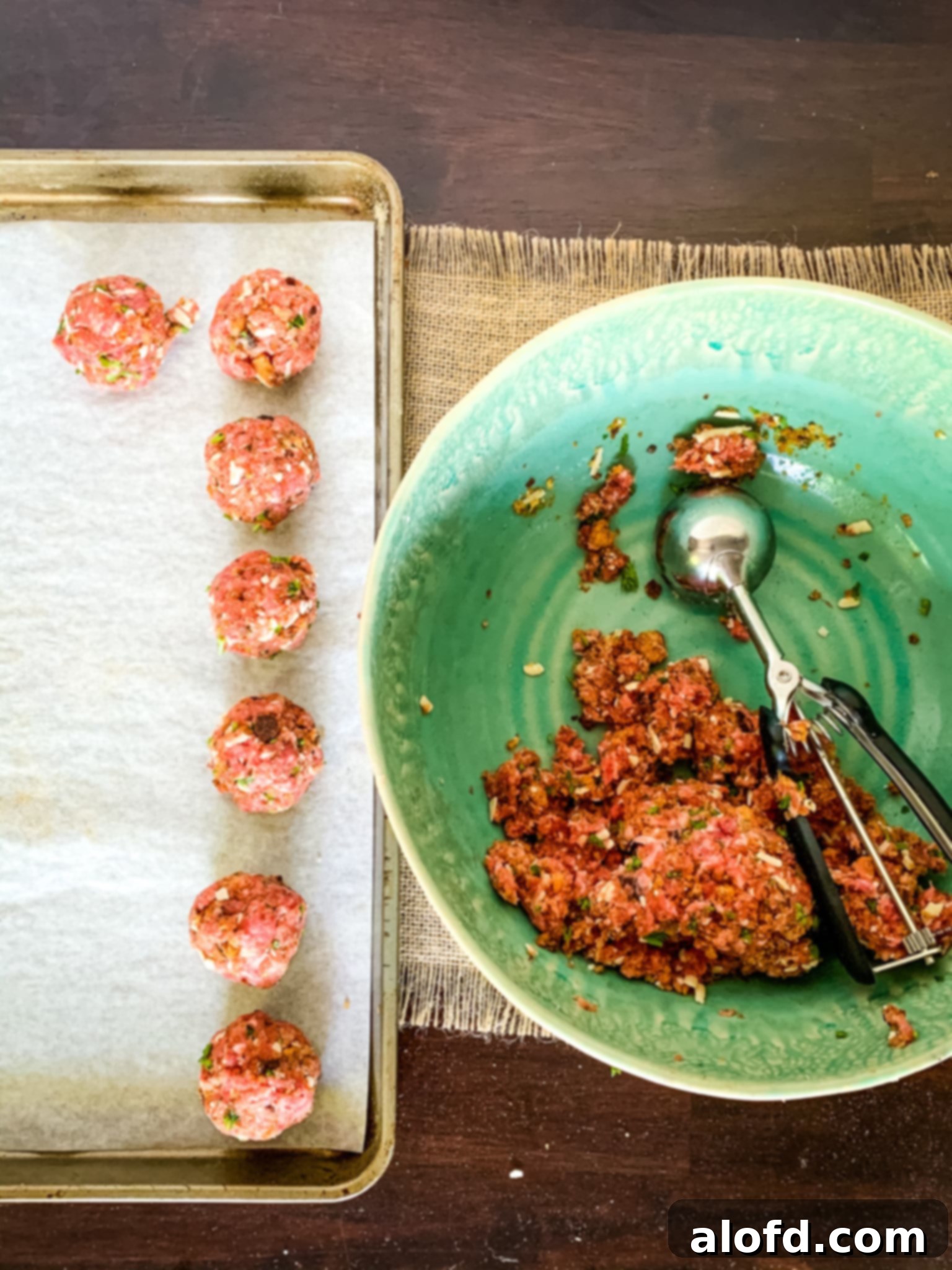 Hearty Meatball Marinara 4 Uncooked meatballs on a baking sheet, with the remaining meatball mixture in a bowl, ready for shaping.