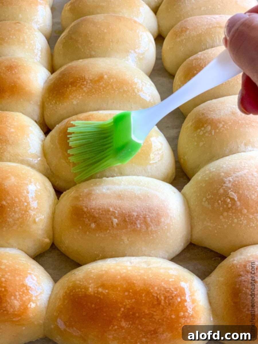 Brushing melted butter over homemade bread rolls.