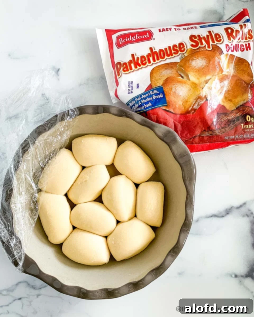 Risen Parker House rolls dough in a round casserole dish, ready for baking.