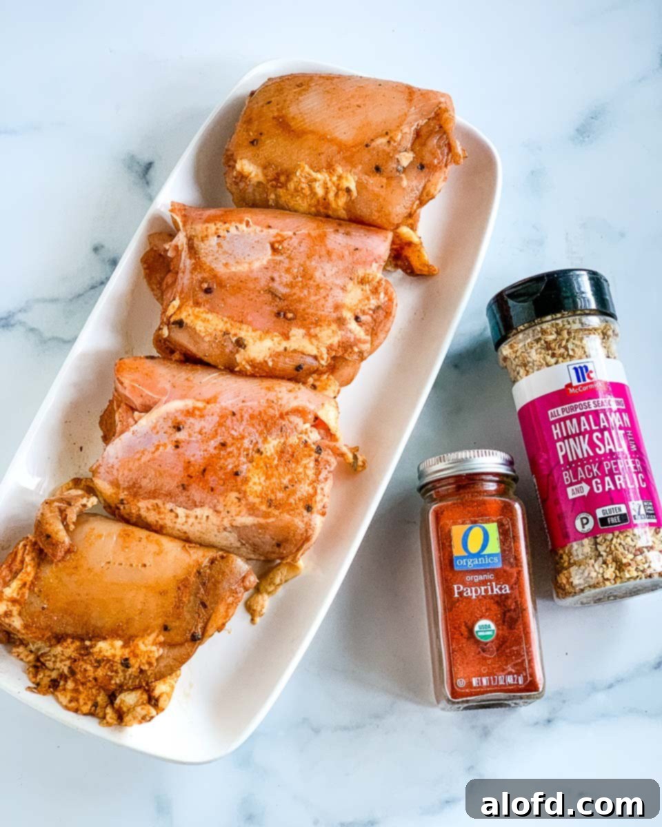 Homestyle Gravy Chicken Thighs 4 Raw chicken thighs seasoned with all-purpose seasoning and vibrant red paprika, ready for cooking.