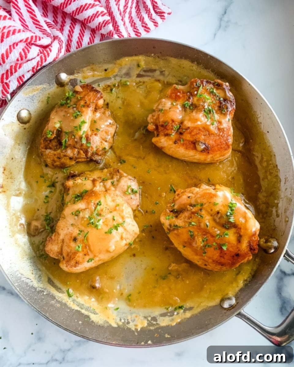 Homestyle Gravy Chicken Thighs 7 Four golden-brown pan-seared chicken pieces resting in a stainless steel skillet, ready to be smothered in gravy.