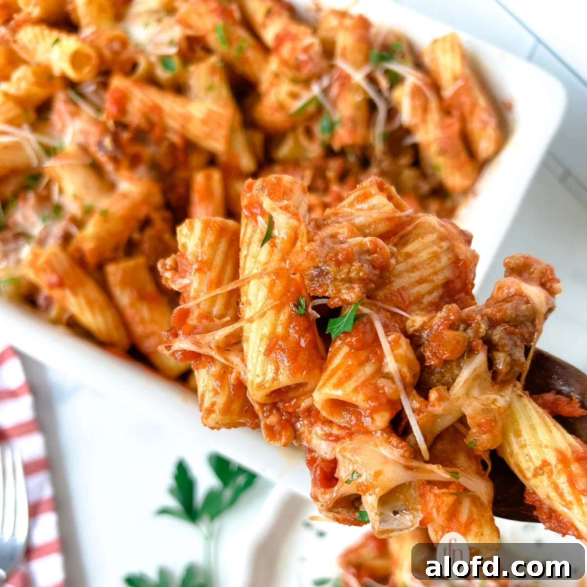 Baked rigatoni pasta casserole, shown closeup on a fork, highlighting the melty cheese and hearty sauce.