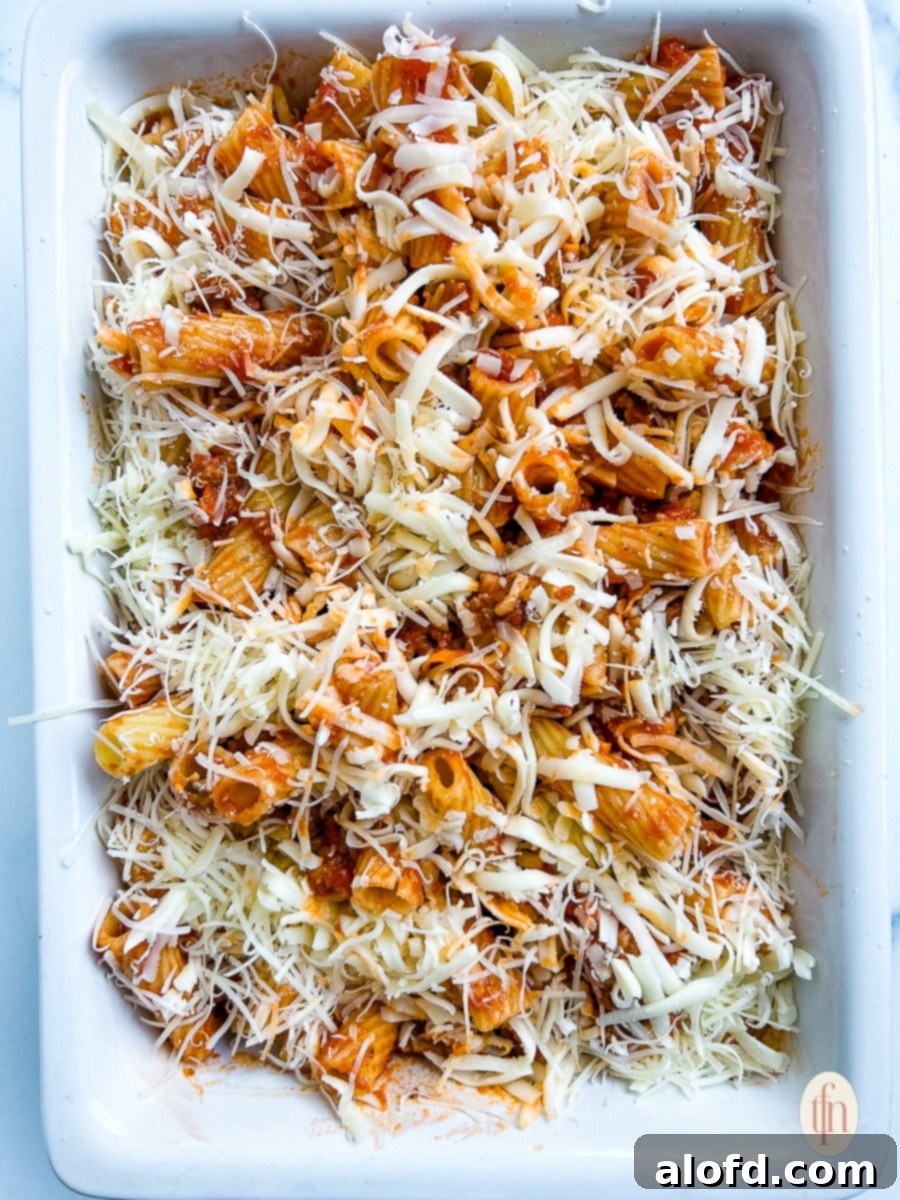 Assembled Italian casserole, layered with pasta, sauce, sausage, and cheese, ready for baking.
