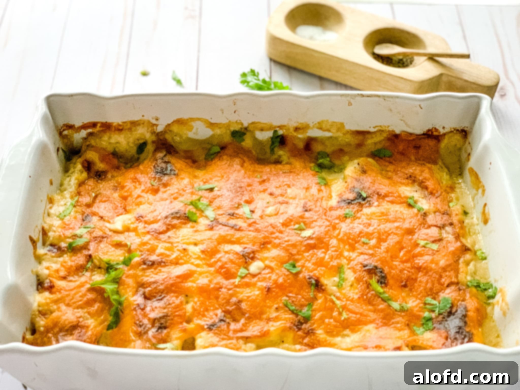 Luscious Sour Cream Chicken Enchiladas 11 casserole dish with creamy chicken enchiladas and a salt and pepper cellar at the side.