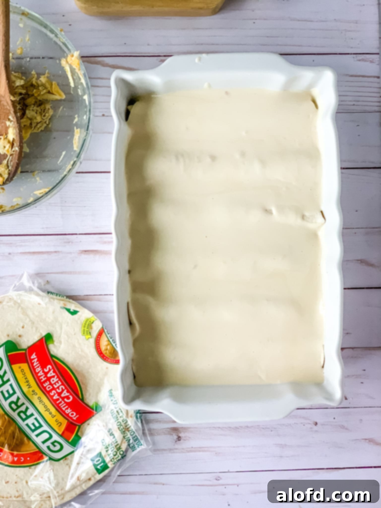 Luscious Sour Cream Chicken Enchiladas 10 ready to bake enchiladas in a white baking dish.