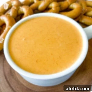 A bowl of creamy Pretzel Cheese Dip, perfectly paired with a mound of golden soft pretzels, ready for snacking.