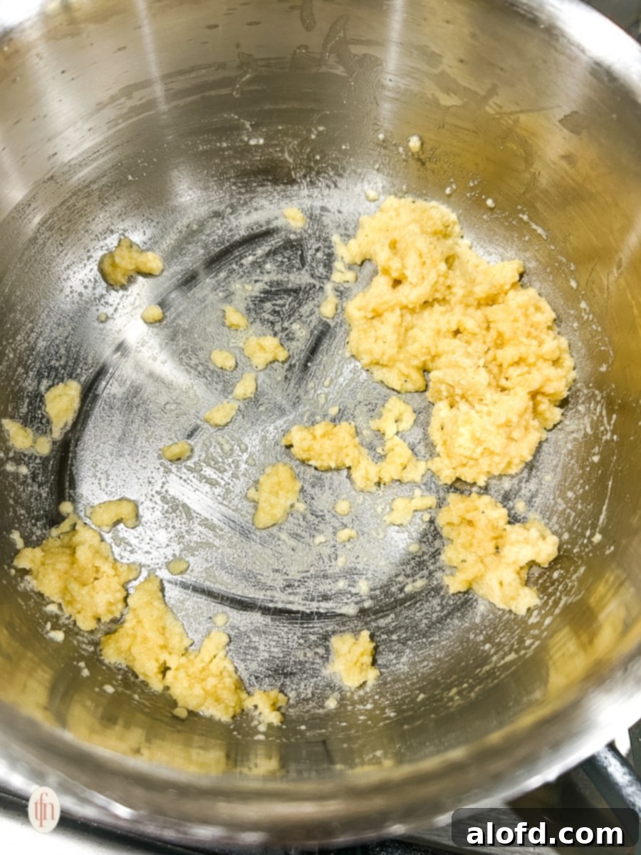 Melted butter and flour creating a roux in a saucepan, the foundation of a rich cheese sauce.