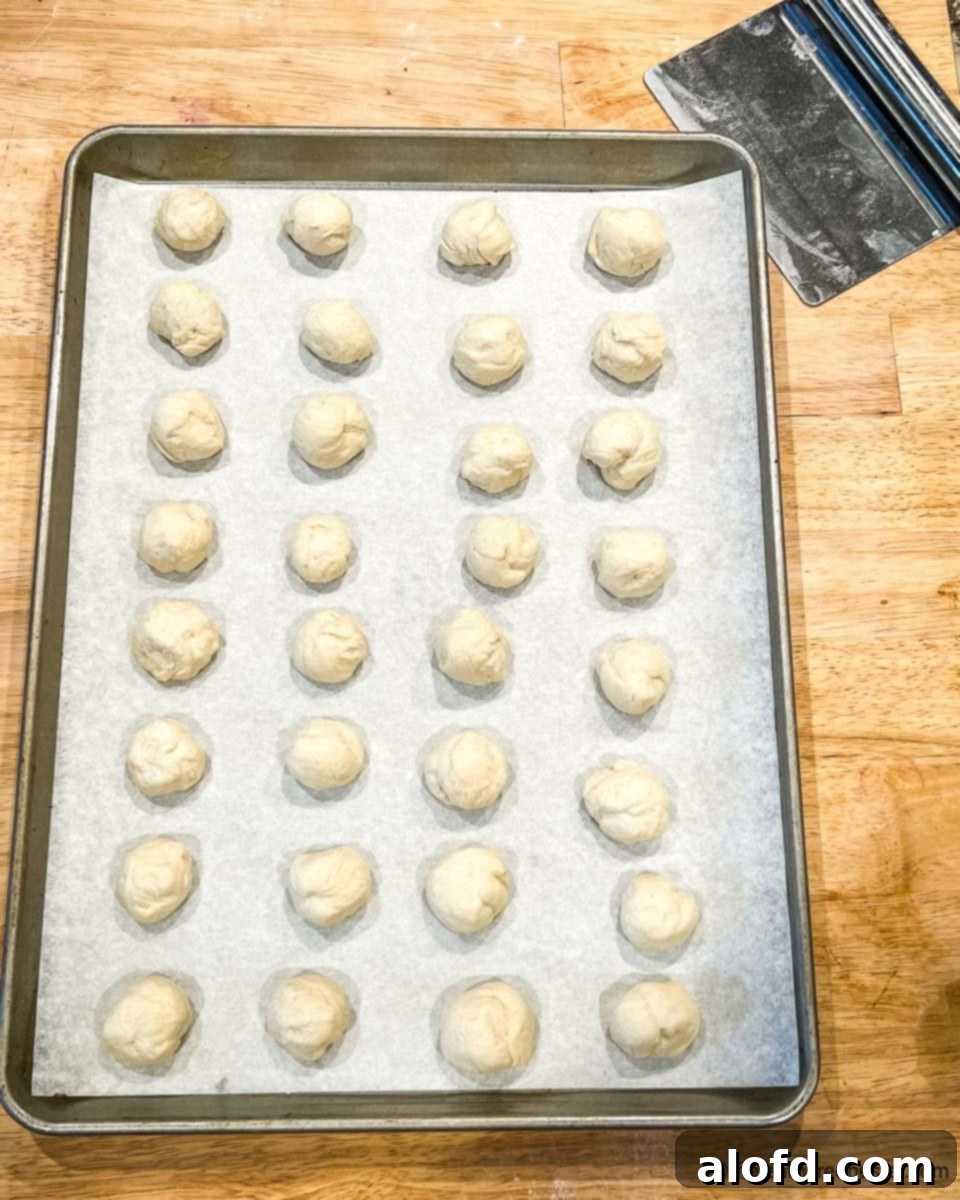 Pretzel Poppers 6 A baking sheet filled with neatly cut and shaped frozen bread dough balls, ready for rising.