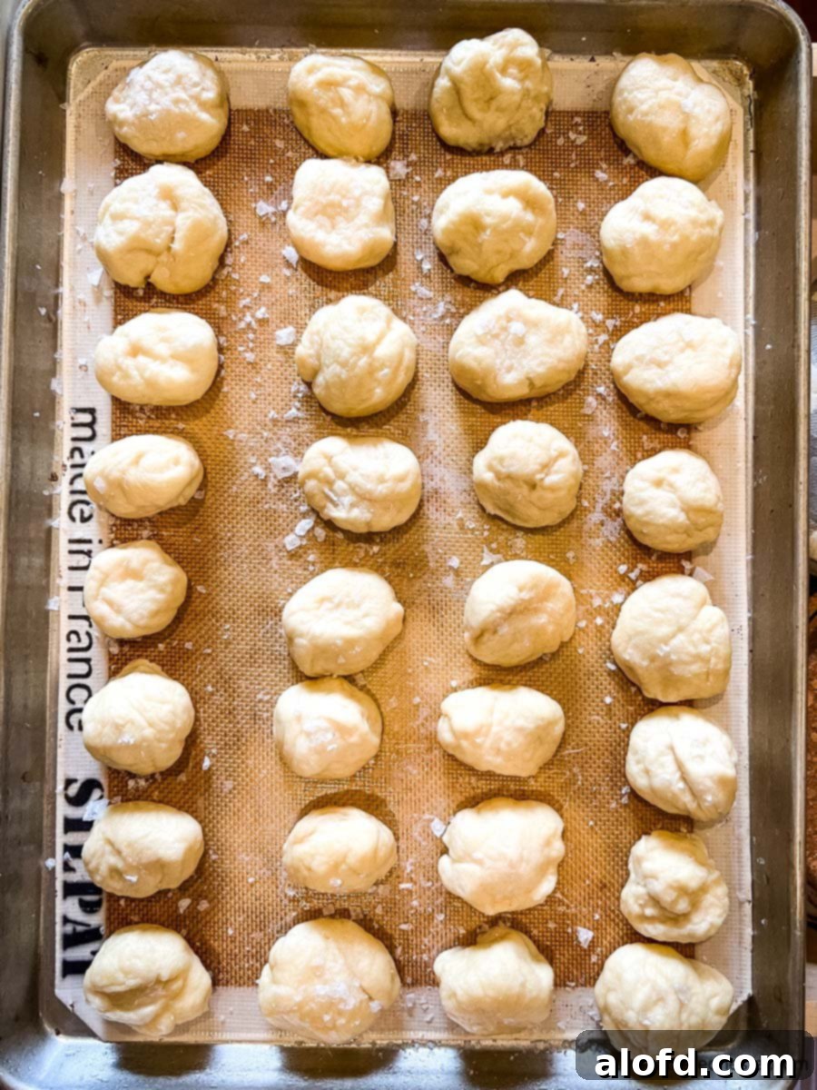 Pretzel Poppers 8 A baking sheet covered with a silicone baking mat, holding recently dipped dough for pretzel balls.