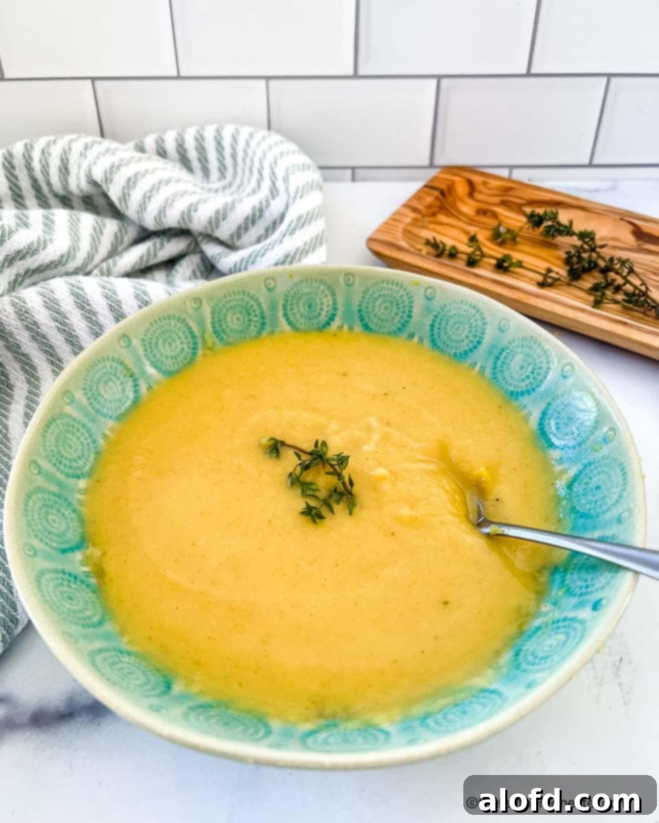 Creamy Instant Pot Acorn Squash Soup 11 Pureed winter vegetable chowder in a blue bowl, garnished with fresh herbs.