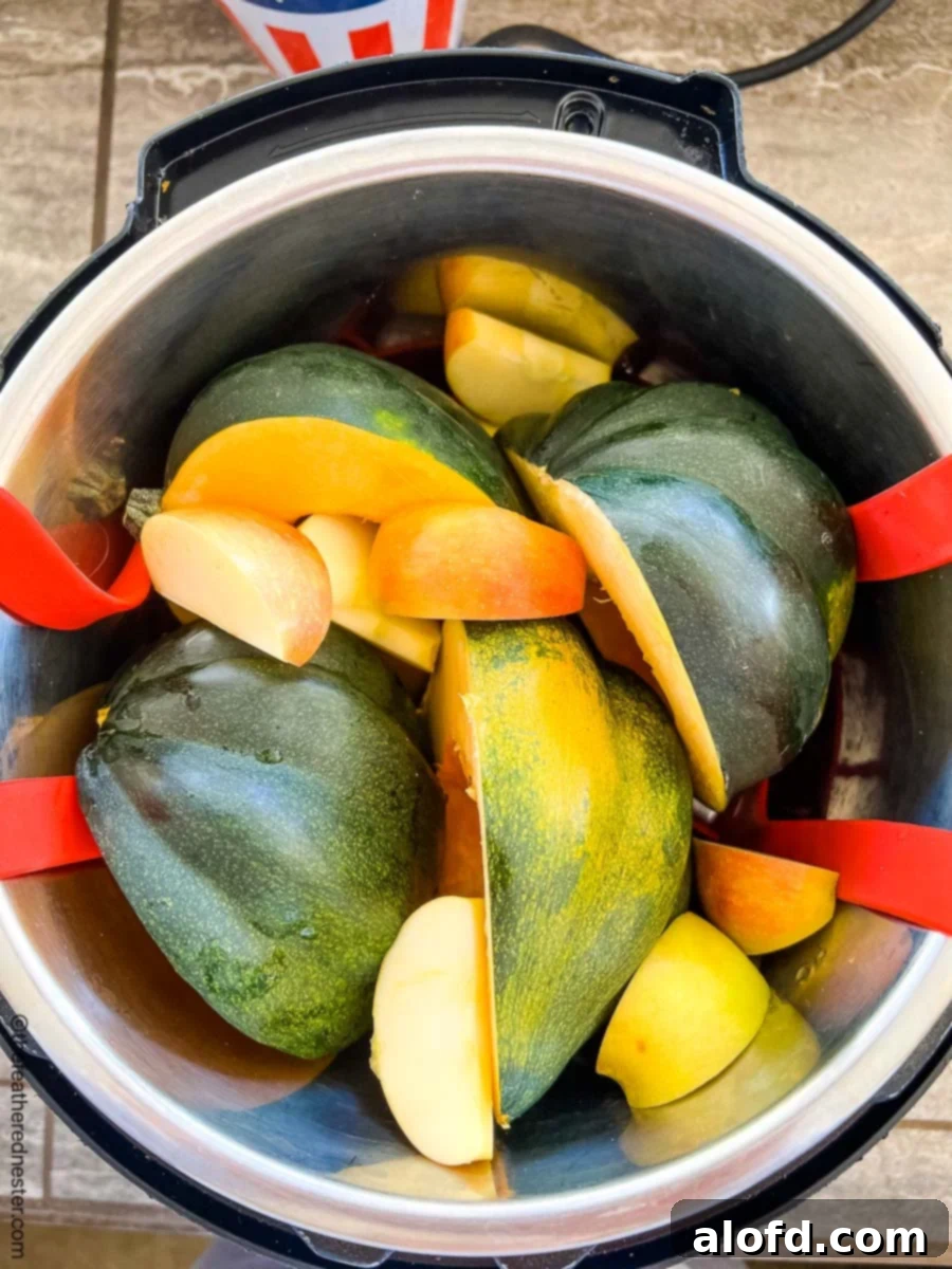 Creamy Instant Pot Acorn Squash Soup 7 An Instant Pot filled with cut acorn squash and an apple, ready for pressure cooking.