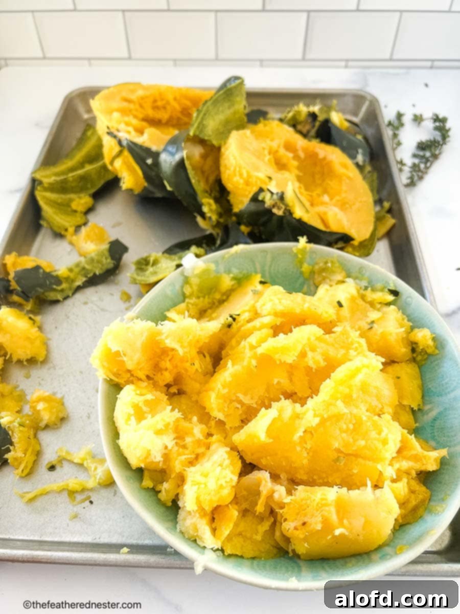 Creamy Instant Pot Acorn Squash Soup 9 Scooping out the softened flesh from a roasted acorn squash half with a spoon.