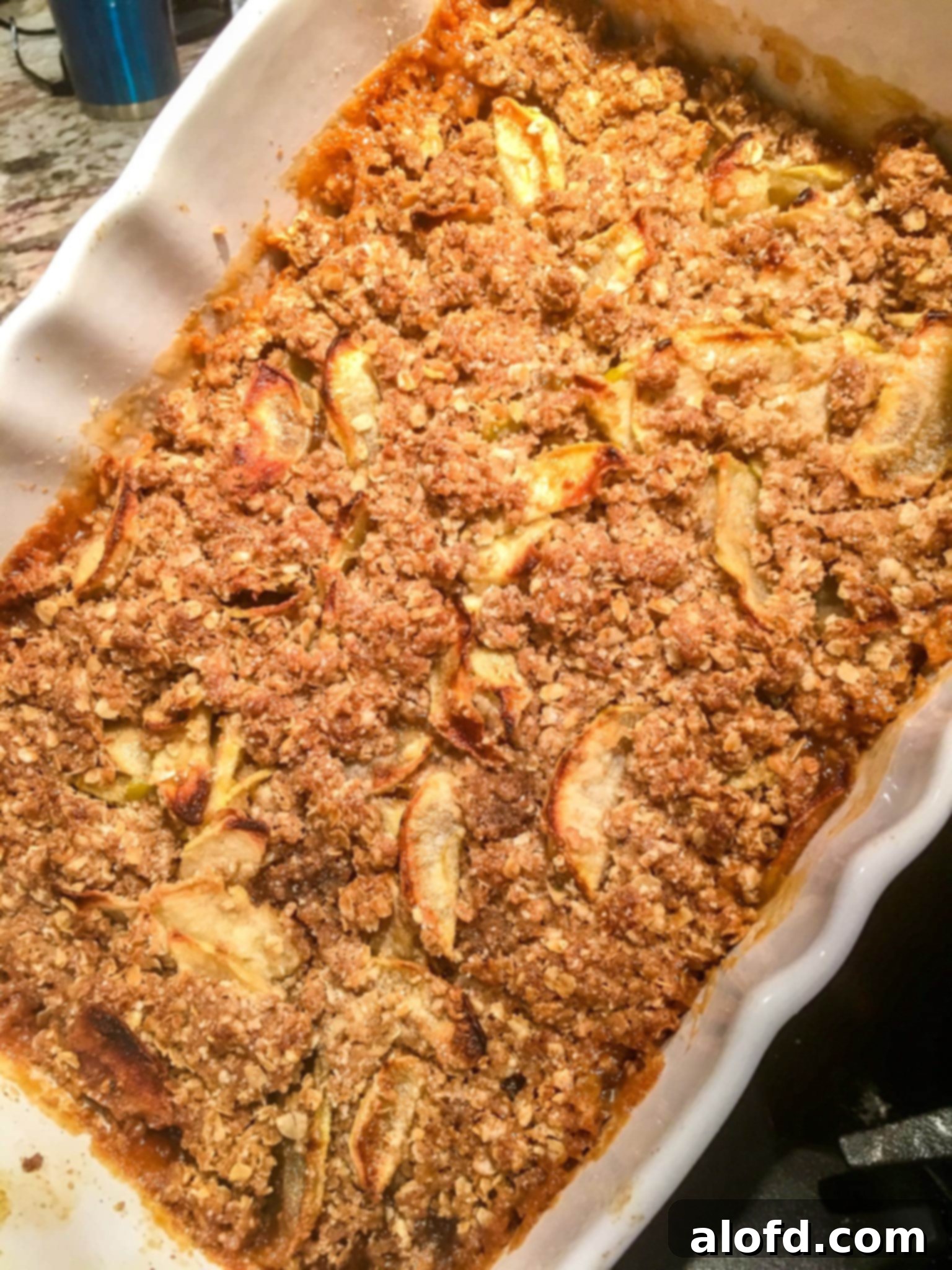 A golden brown apple crisp, fresh from the oven, served in a rustic casserole dish.