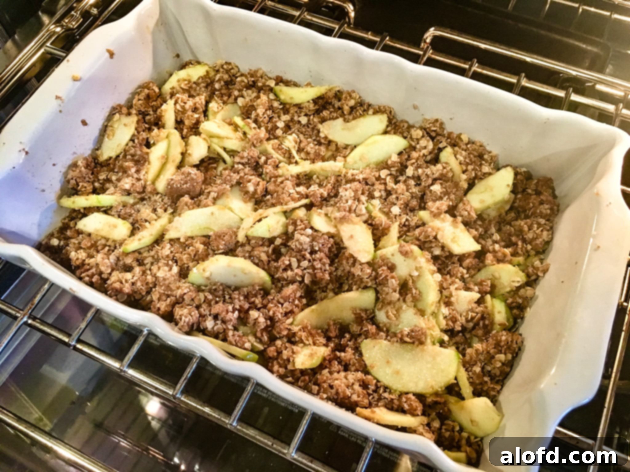 A freshly baked apple crisp, golden brown and bubbly, served in a white serving bowl, ready to enjoy.