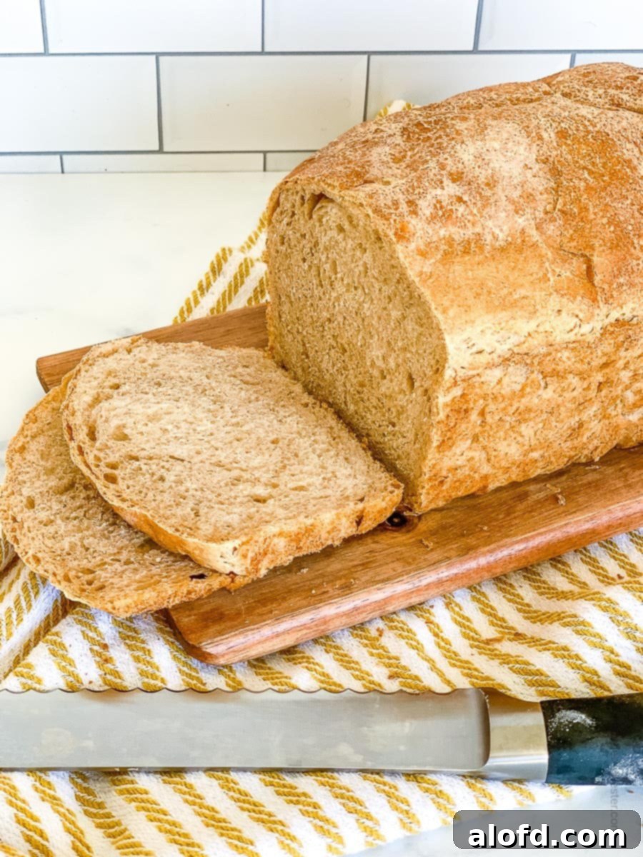 Slice of whole wheat sourdough bread on a wooden board with a bread knife beside it, showcasing its tender crumb and golden crust.