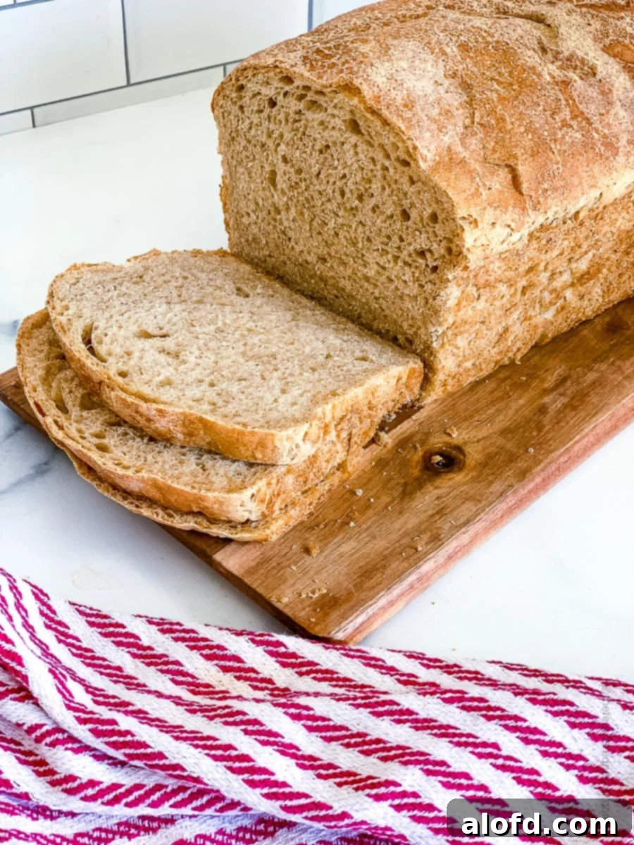 Slice whole wheat sourdough bread on top of a wooden board and a red striped cloth at the side, presenting a rustic appeal.