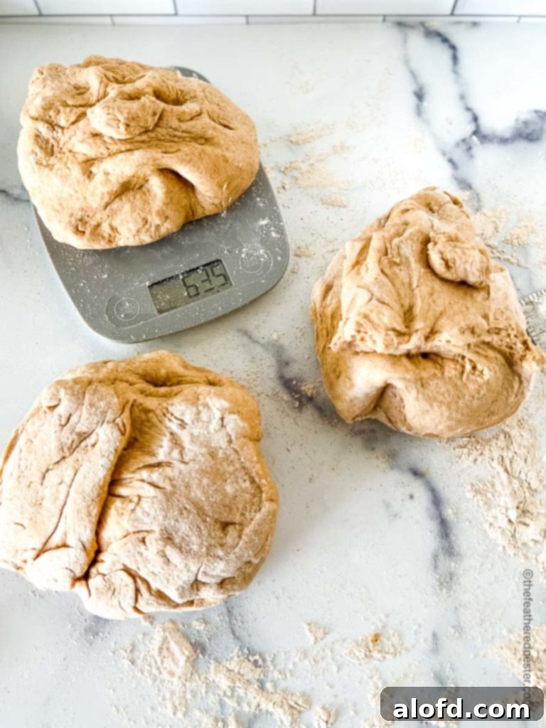 A close-up shot of individual portions of whole wheat sandwich bread dough being weighed on a kitchen scale, ensuring consistent loaf sizes for baking.