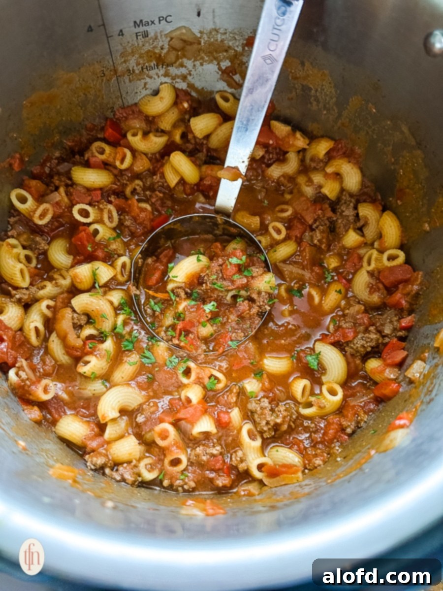 A ladle serving cooked chili mac directly from the Instant Pot, ready for plating.