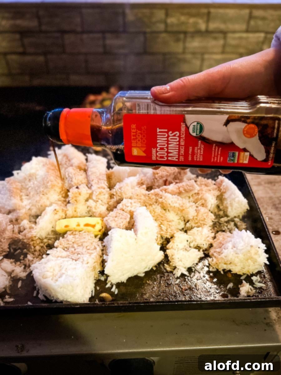 Sizzling Blackstone Fried Rice 8 Pouring coconut aminos over rice on Blackstone