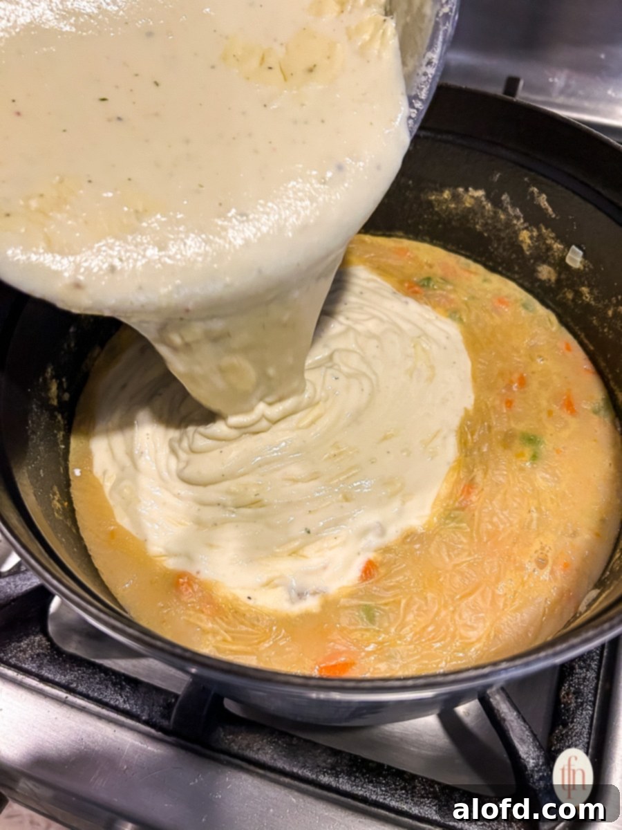 Pouring the roux mixture into the main soup pot on the stovetop.