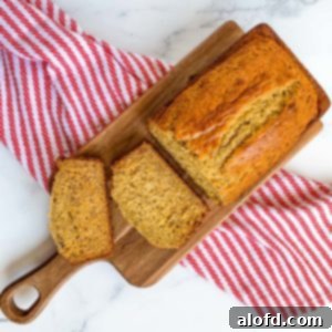 Effortless Self-Rising Banana Bread 11 sliced self rising flour banana bread on a wooden board with a red and white kitchen towel.